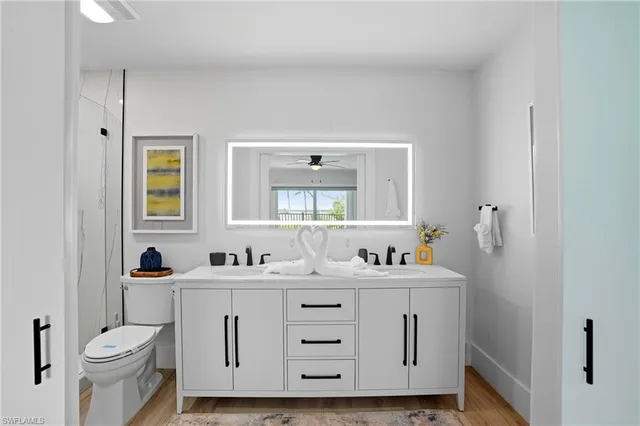 a bathroom with a double vanity sink toilet and mirror