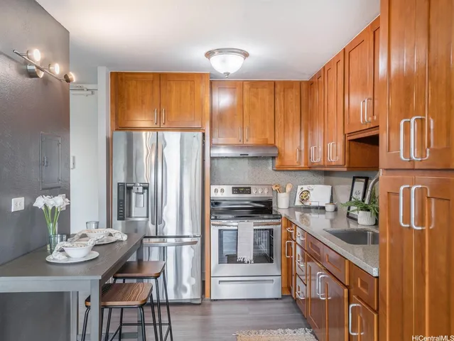 a kitchen with stainless steel appliances granite countertop a refrigerator a sink dishwasher and wooden cabinets with wooden floor