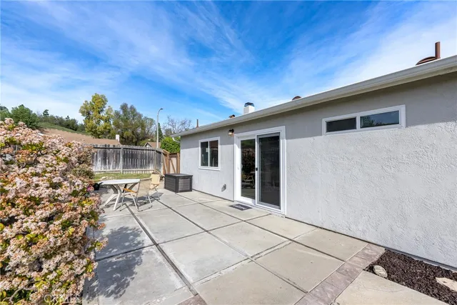 a backyard of a house with table and chairs with wooden fence