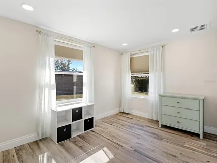 a view of a bedroom with wooden floor and windows