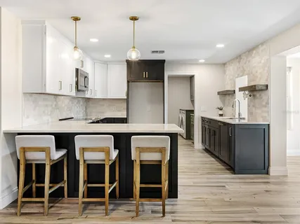 a kitchen with stainless steel appliances kitchen island granite countertop a table chairs refrigerator and sink