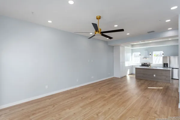 a view of empty room with wooden floor and fan