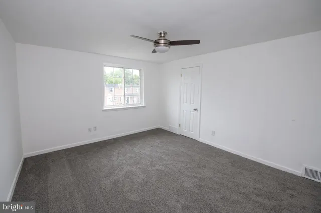 an empty room with a window and a fan
