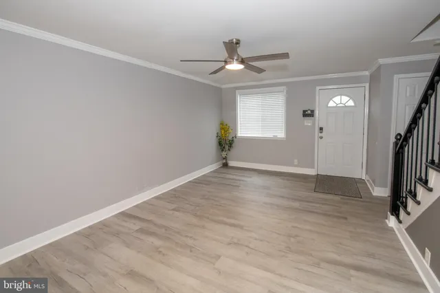 an empty room with wooden floor and a ceiling fan