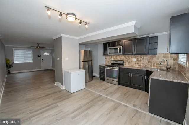 a kitchen with granite countertop a stove top oven a sink dishwasher and a refrigerator