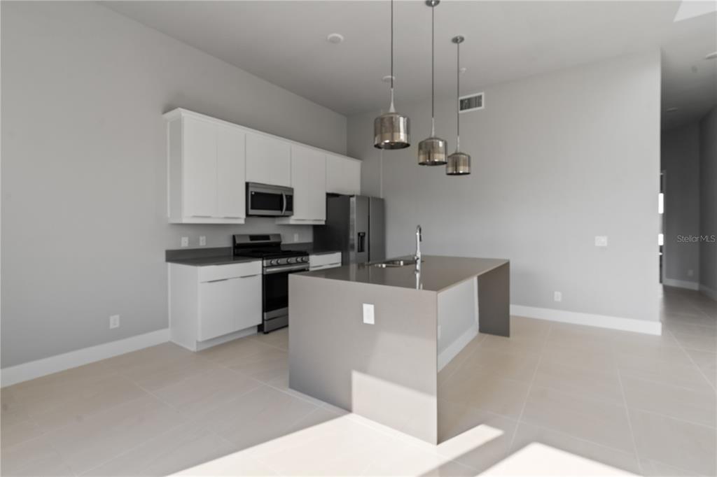 7770 Sandy Ridge Drive, Unit 239 Reunion, FL 34747 - Photo 5 of 49 a living room with stainless steel appliances kitchen island a white counter space a sink and appliances