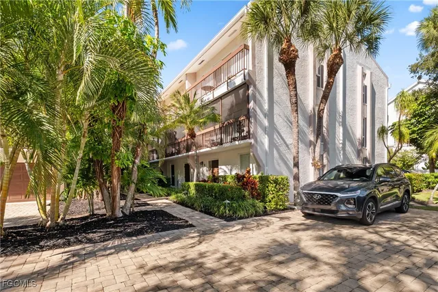 a view of a street with potted plants and large trees