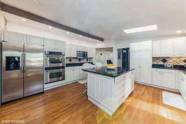 a kitchen with granite countertop a refrigerator and a stove top oven