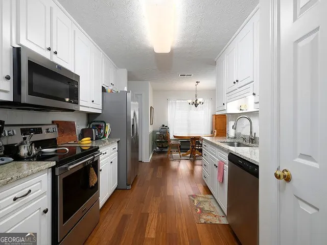 a kitchen with stainless steel appliances a stove top oven a sink dishwasher and a refrigerator