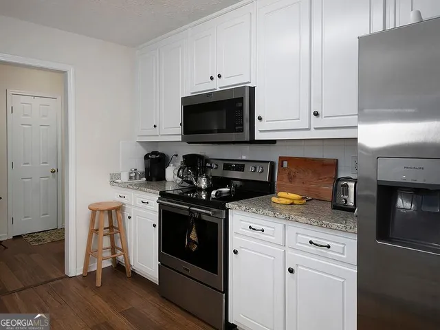 a kitchen with stainless steel appliances granite countertop a stove a sink and a microwave