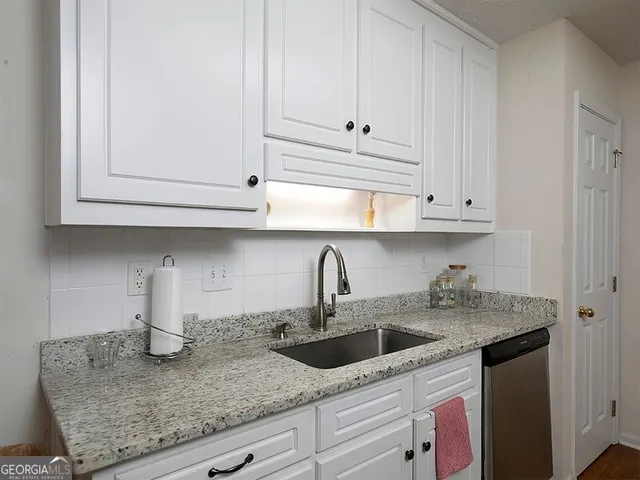 a kitchen with stainless steel appliances granite countertop white cabinets and a sink