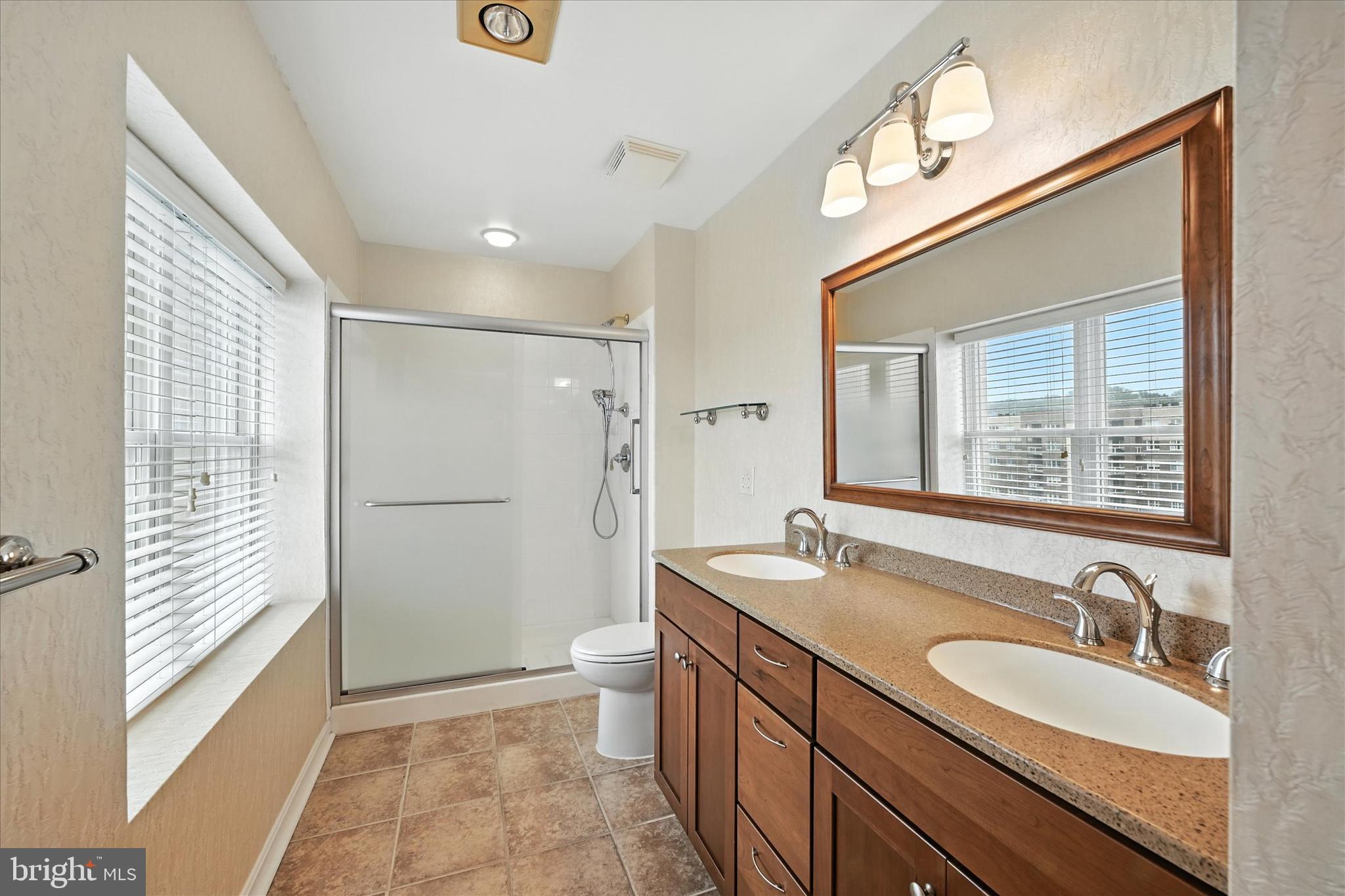 12240 Roundwood Road, Unit 808 Lutherville-Timonium, MD 21093 - Photo 24 of 31 a bathroom with a granite countertop sink mirror and a shower