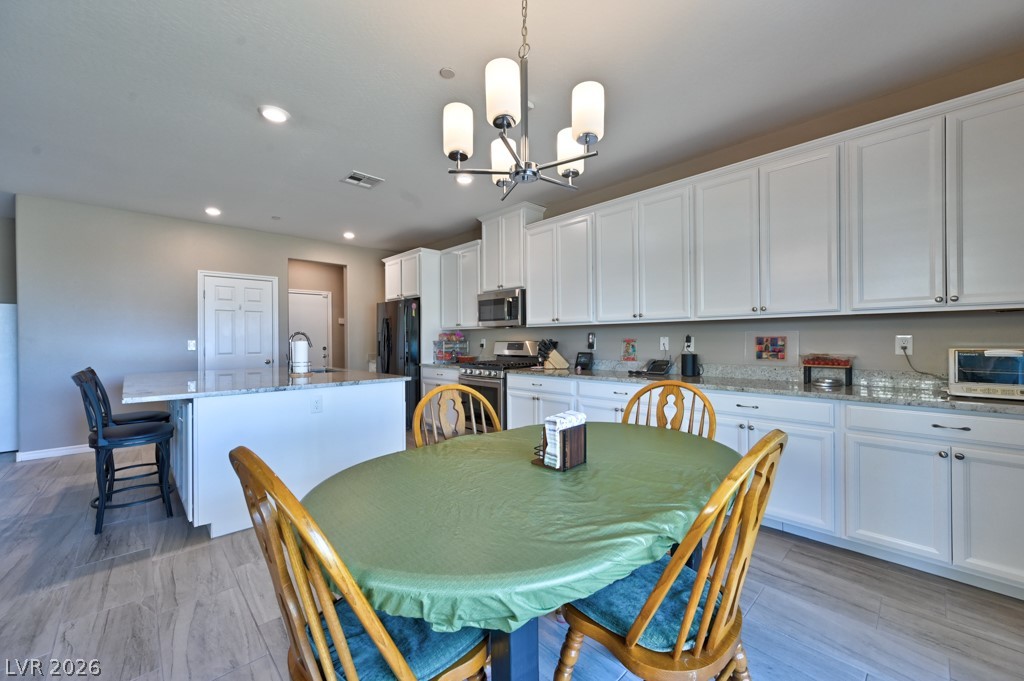 1054 Langston Ranch Avenue Henderson, NV 89002 - Photo 22 of 82 Dining space is open and can fit a very large table. Hanging light fixture. Cabinets cover the entire wall. Plenty of room for all of your kitchen gadgets and appliances.