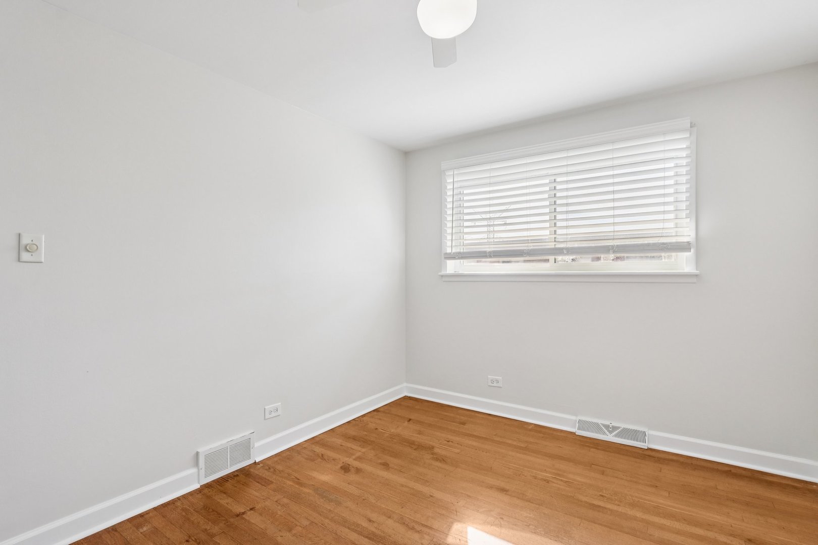 8666 Gregory Lane, Unit C Des Plaines, IL 60016 - Photo 13 of 30 a view of an empty room with wooden floor and a window