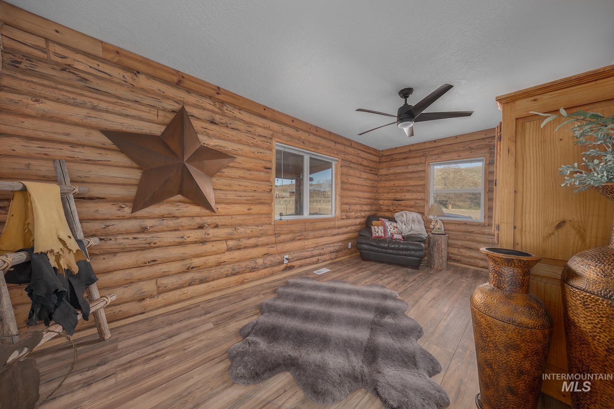 1855 Jones Road Weiser, ID 83672 - Photo 18 of 33 Sitting room featuring rustic walls, a textured ceiling, a ceiling fan, and hardwood / wood-style floors