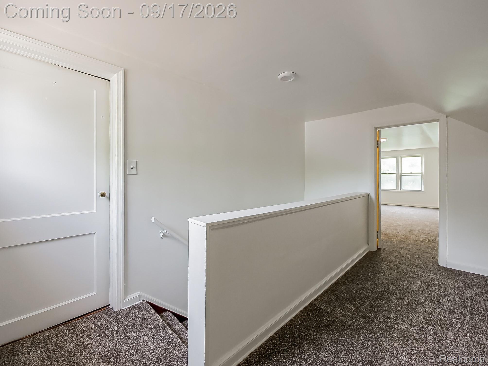 14102 Toepfer Road Warren, MI 48089 - Photo 17 of 39 Carpeted hallway with a white panel door, white painted walls, and a white stair railing