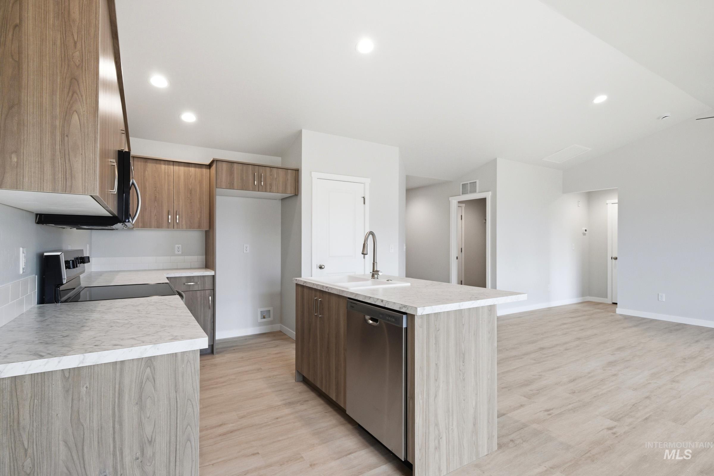 16632 North Shorthorn Loop Nampa, ID 83651 - Photo 7 of 17 Modern kitchen featuring wood-finish cabinetry, light-toned countertops, and a subway tile backsplash