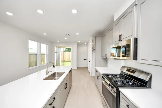 a kitchen with stainless steel appliances granite countertop a sink stove and refrigerator