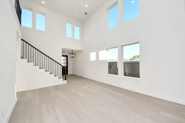 a view of an empty room with wooden floor and windows