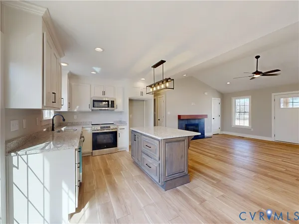 a kitchen with stainless steel appliances granite countertop a stove top oven a sink dishwasher a refrigerator and a dining table with wooden floor