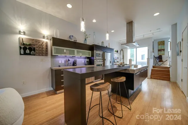 a kitchen with stainless steel appliances kitchen island granite countertop a sink a stove a dining table and chairs