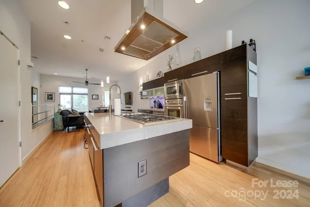 a kitchen with stainless steel appliances granite countertop a refrigerator a stove and a sink