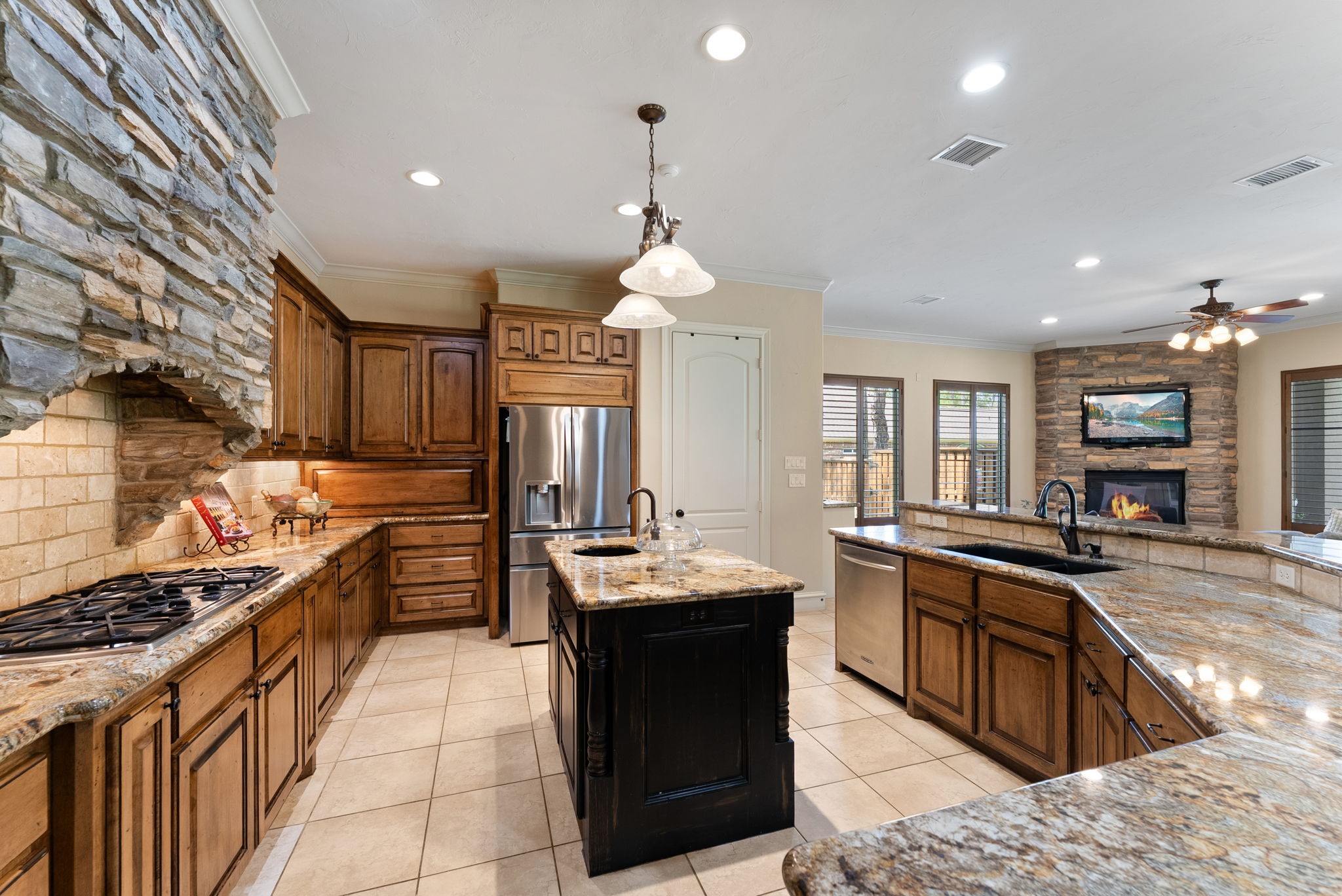 3907 Rayford Road Spring, TX 77386 - Photo 14 of 38 Thoughtfully designed for both entertaining and daily living, the space offers an oversized island with prep sink and decorative lighting, a wraparound stone breakfast bar with seating, abundant storage including a dedicated small appliance cabinet, and a walk-in pantry.