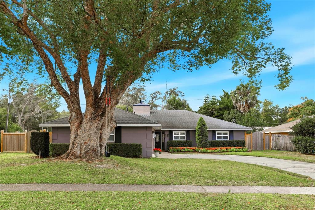 a front view of a house with a garden and trees