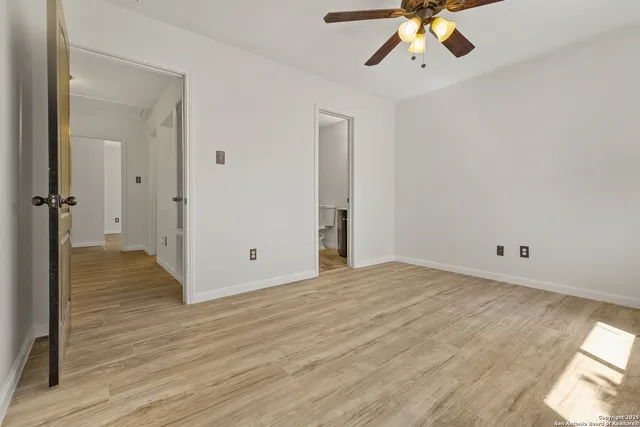 an empty room with wooden floor fan and windows