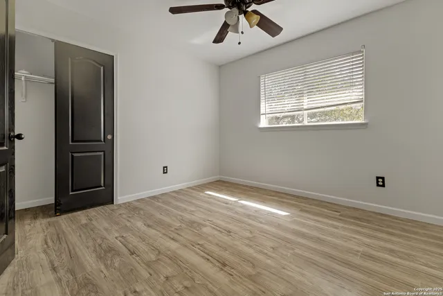 a view of empty room with wooden floor and fan