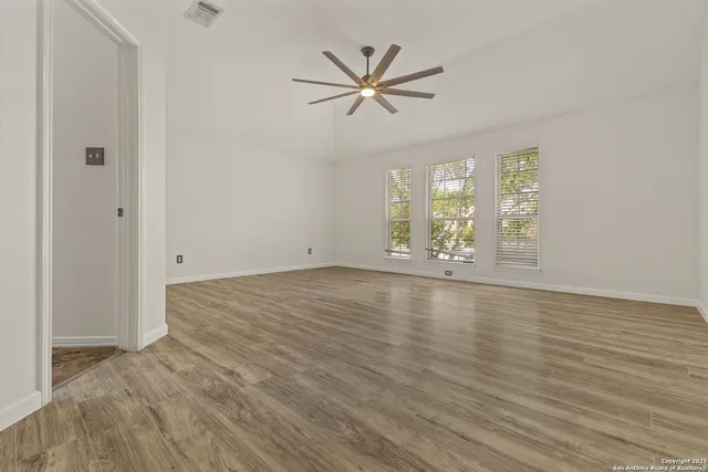 a view of an empty room with window and wooden floor