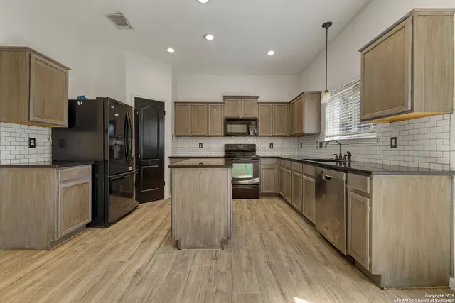 a kitchen with kitchen island granite countertop a sink cabinets and stainless steel appliances