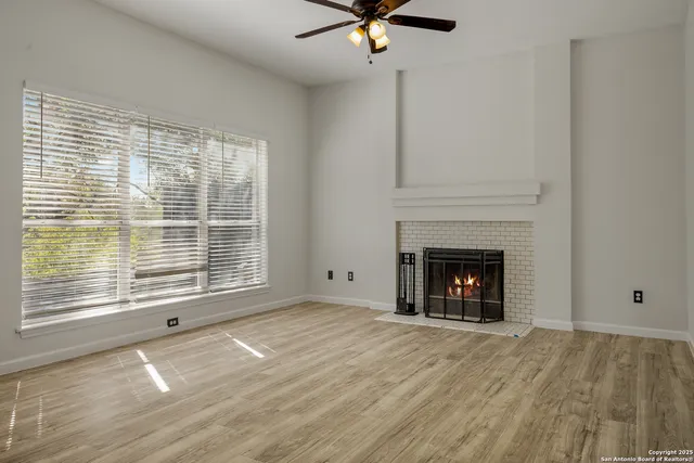 a view of an empty room with wooden floor fireplace and a window
