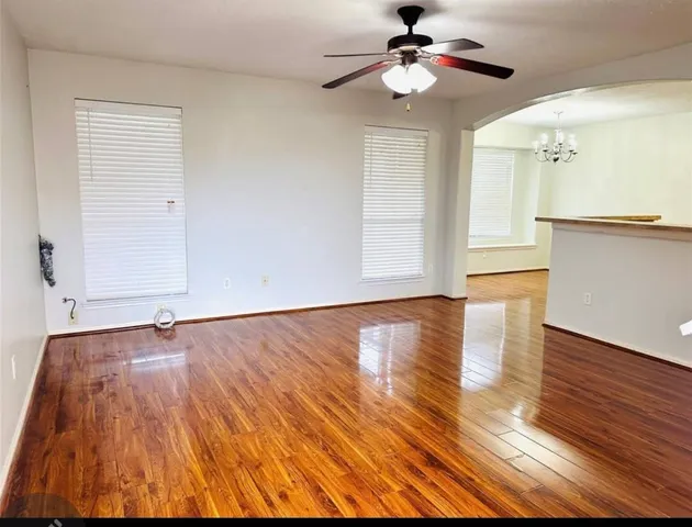 a view of empty room with wooden floor and fan