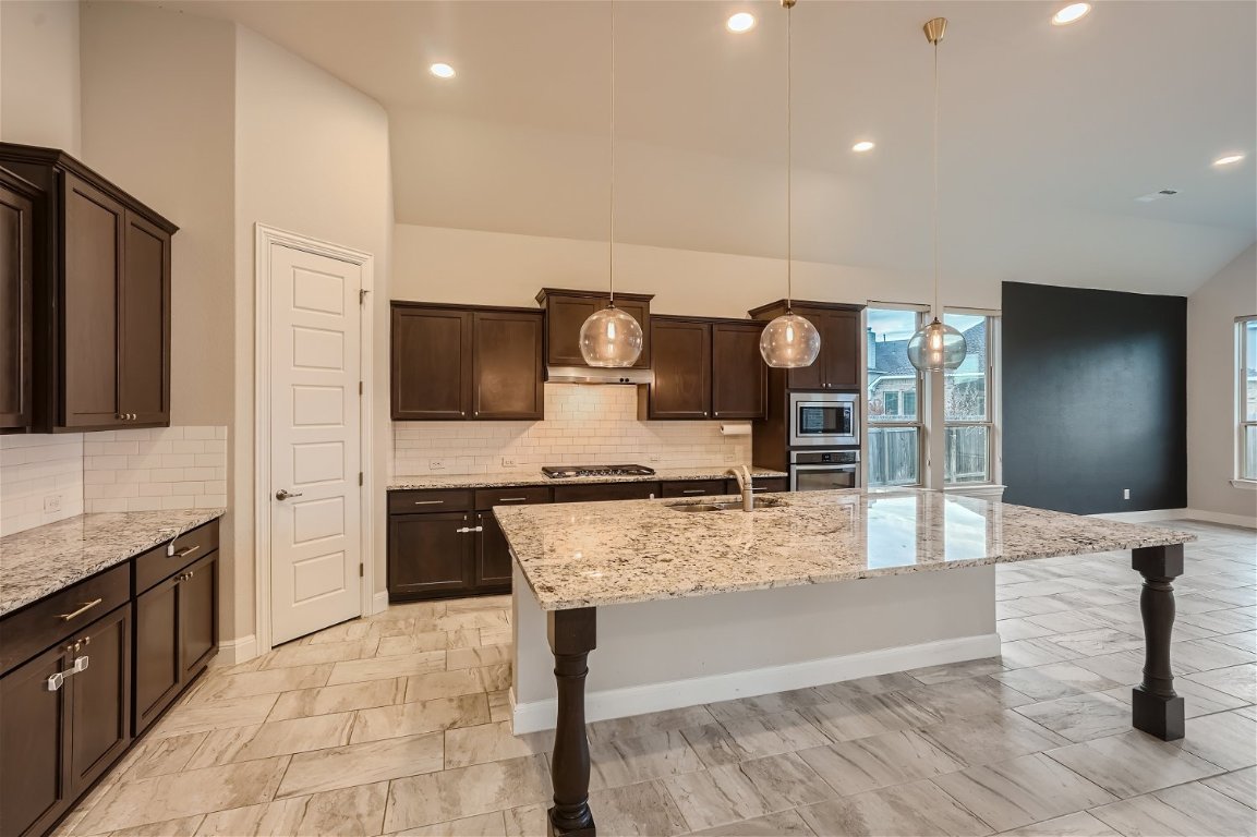 a large kitchen with stainless steel appliances granite countertop a stove refrigerator and microwave