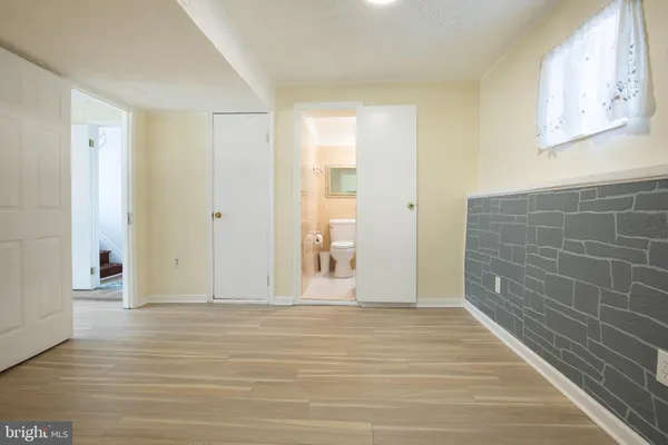 a view of an empty room with wooden floor and a bathroom