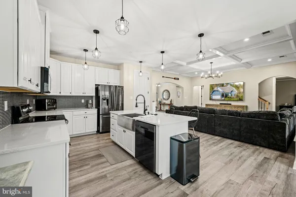 a kitchen with stainless steel appliances granite countertop a refrigerator a stove a microwave oven a sink dishwasher and white cabinets with wooden floor