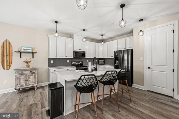 a kitchen with stainless steel appliances a table chairs refrigerator and microwave
