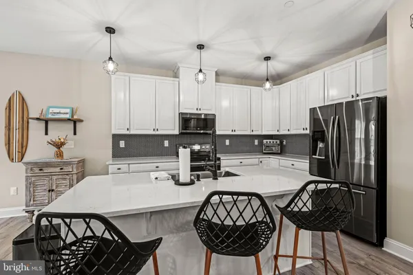 a kitchen with stainless steel appliances granite countertop a dining table chairs stove refrigerator and cabinets