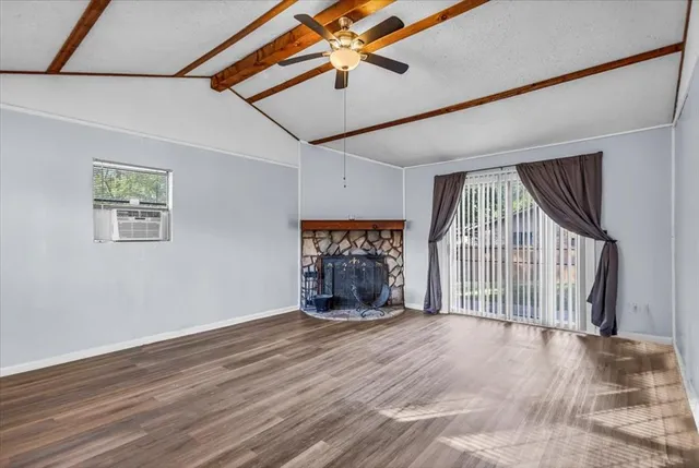 a view of an empty room with a window and wooden floor