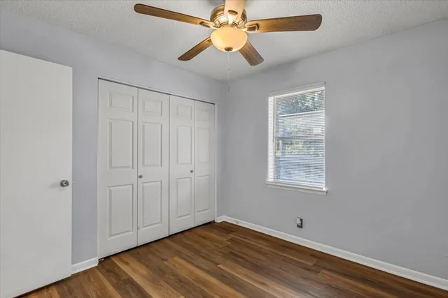 a view of an empty room with window and a chandelier fan