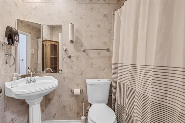 a bathroom with a sink a toilet and shower curtain