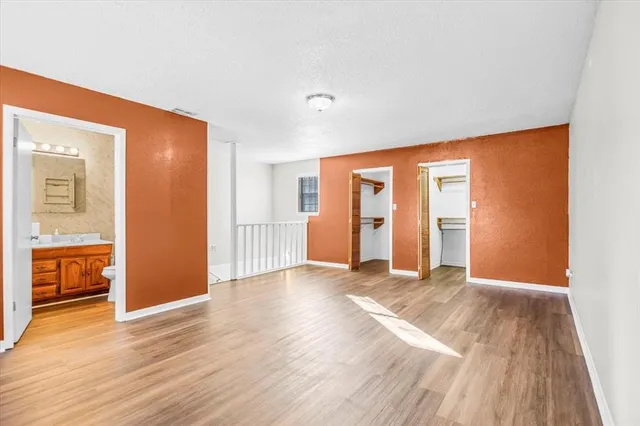 a view of an empty room with wooden floor and windows