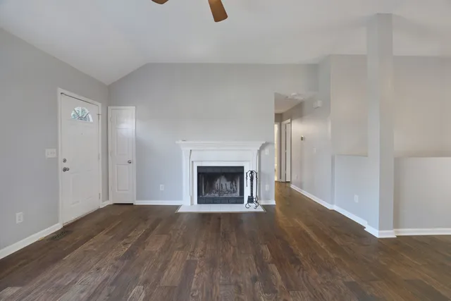 an empty room with wooden floor fireplace and windows