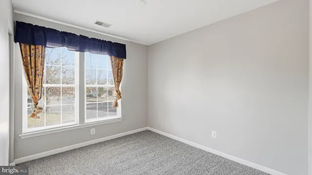 an empty room with windows and fireplace
