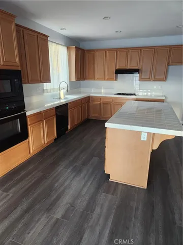 a kitchen with stainless steel appliances a stove a sink dishwasher and a microwave oven with wooden floor