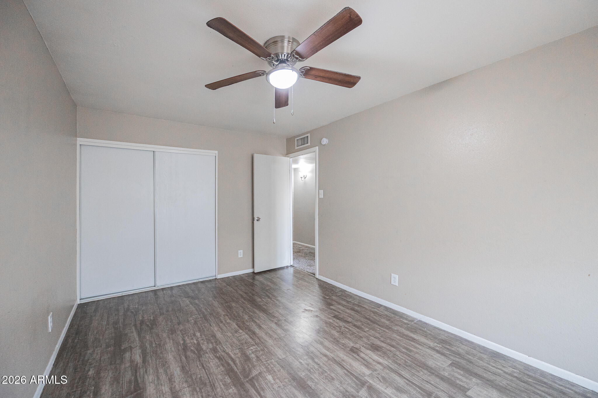 5041 North 39th Lane Phoenix, AZ 85019 - Photo 11 of 15 an empty room with wooden floor and ceiling fan