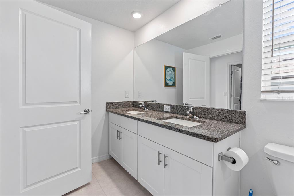 36498 Camp Fire Terrace Zephyrhills, FL 33541 - Photo 19 of 38 a bathroom with a granite countertop sink and a mirror