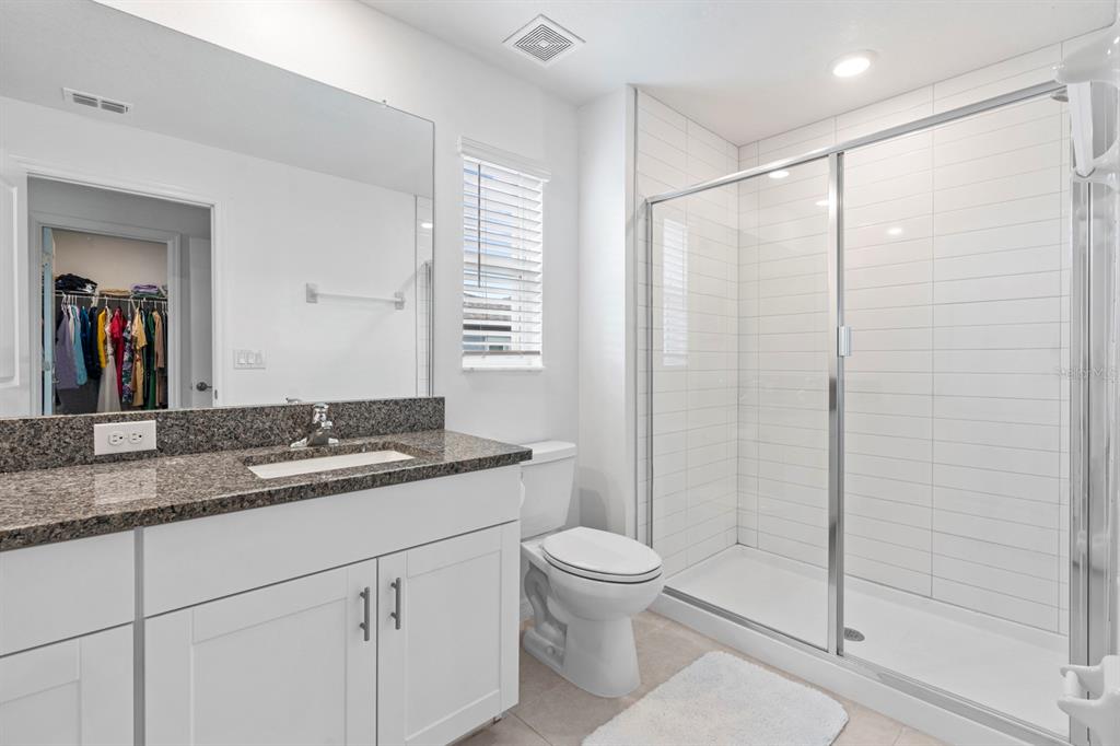 36498 Camp Fire Terrace Zephyrhills, FL 33541 - Photo 20 of 38 a bathroom with a granite countertop sink a toilet and shower