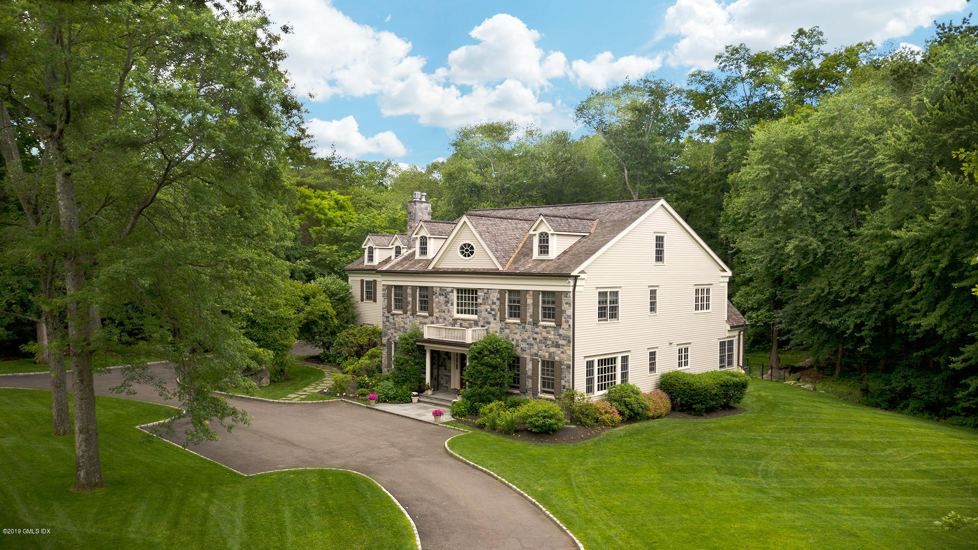 a view of a house with a big yard plants and large trees